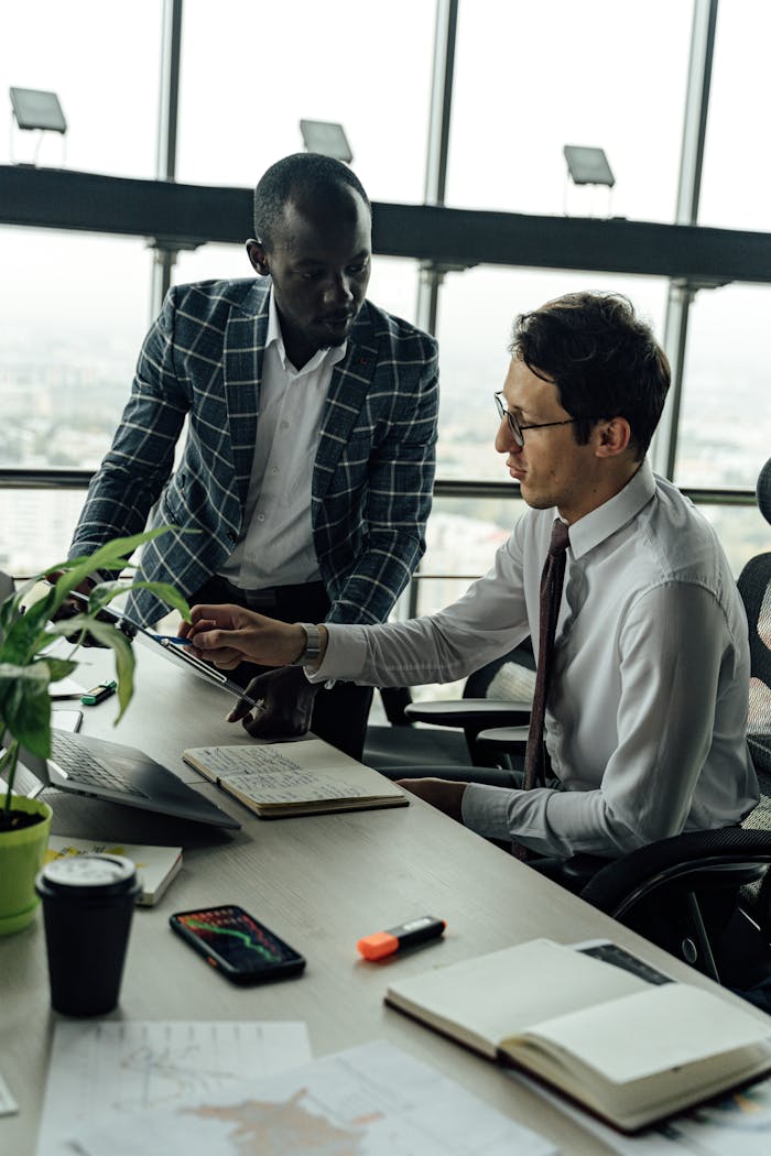 services-04 Two businessmen discussing projects in a modern high-rise office setting.